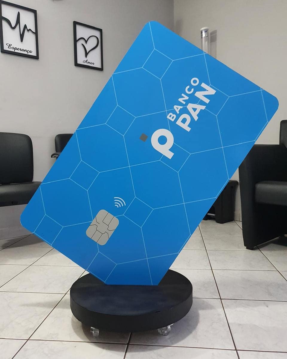 Display de piso do Banco PAN em formato de cartão gigante azul, montado sobre base circular com rodízios