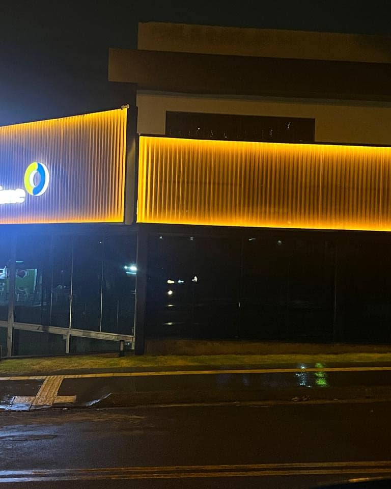 Fachada da Chopp Time à noite, com perfil de LED contornando o volume e o letreiro aceso no canto