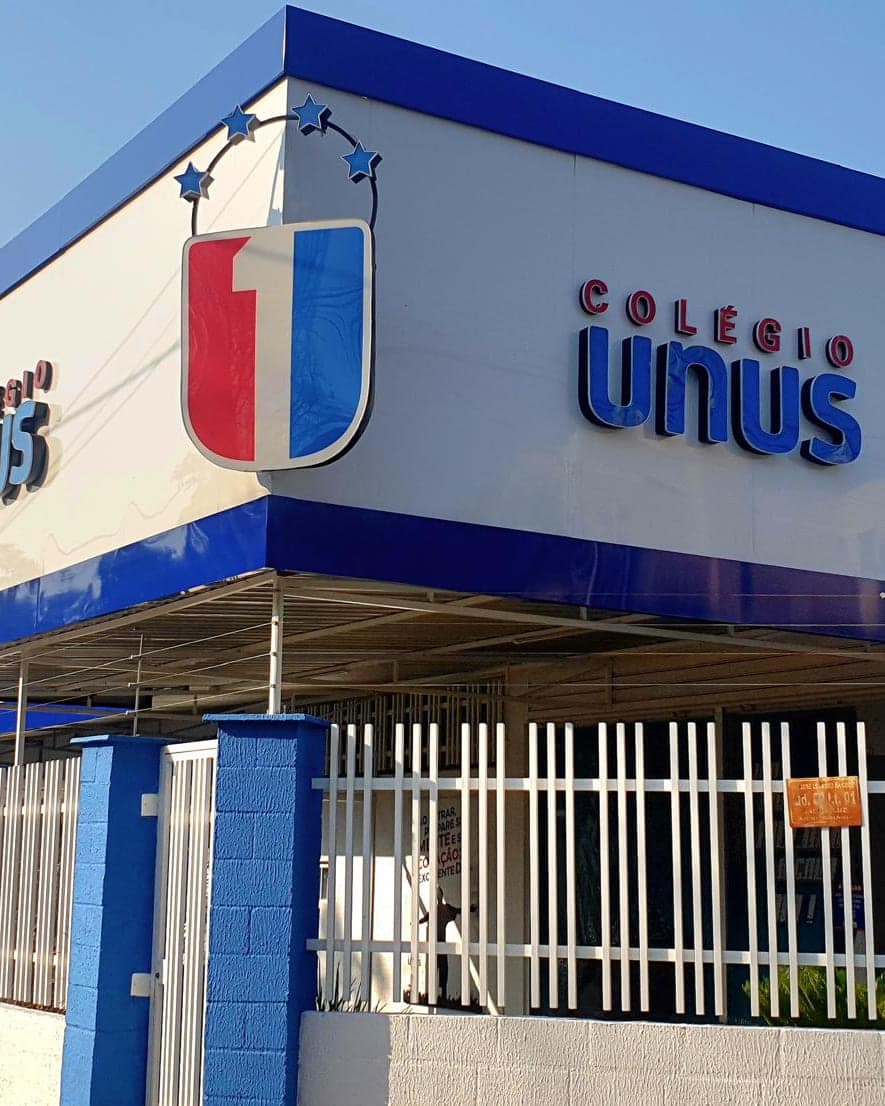 Fachada do Colégio Unus em ACM branco e azul, com o símbolo e as letras caixa aplicadas no volume de esquina