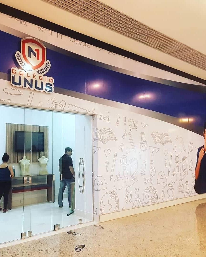 Loja do Colégio Unus em shopping, com a parede revestida de adesivo ilustrado e a marca em letra caixa sobre a entrada