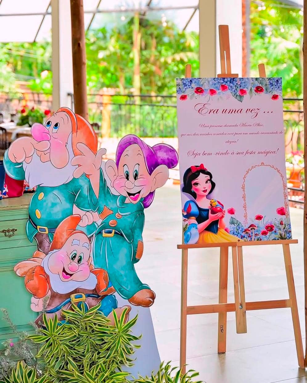 Display recortado dos anões da Branca de Neve ao lado da placa de boas-vindas da Maria Alice sobre cavalete, em festa de dois anos
