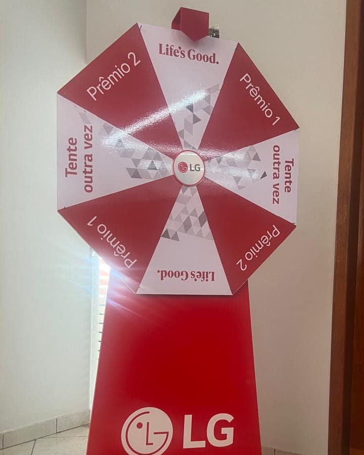 Roleta promocional da LG em vermelho e branco, com setores de prêmio, montada sobre base cônica