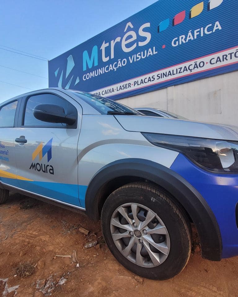 Carro compacto da Moura com adesivagem em azul e branco na lateral, estacionado em frente à M3