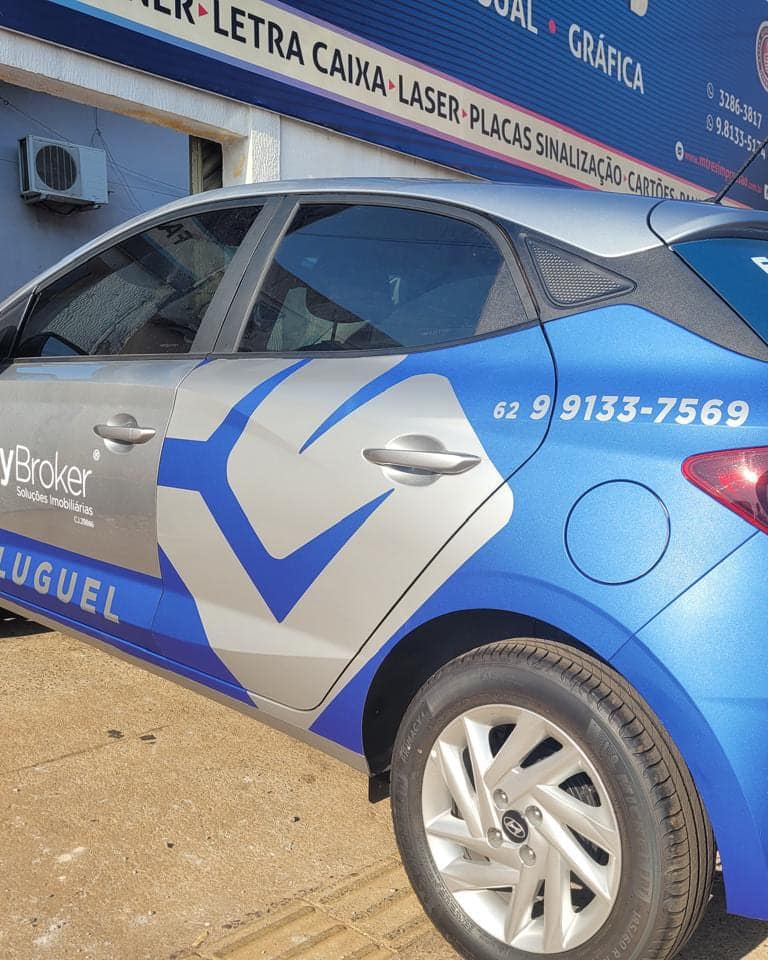 Lateral do carro da MyBroker envelopado em azul e prata, com a marca, o telefone e a palavra Aluguel na porta