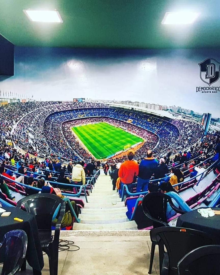 Parede do Democráticos Sports Bar revestida com adesivo impresso de um estádio lotado, do teto ao piso