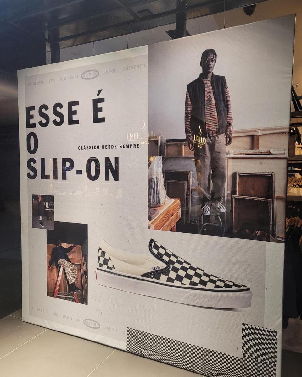 Parede de loja de calçados revestida com adesivo impresso de campanha, com fotos e a frase Esse é o slip-on