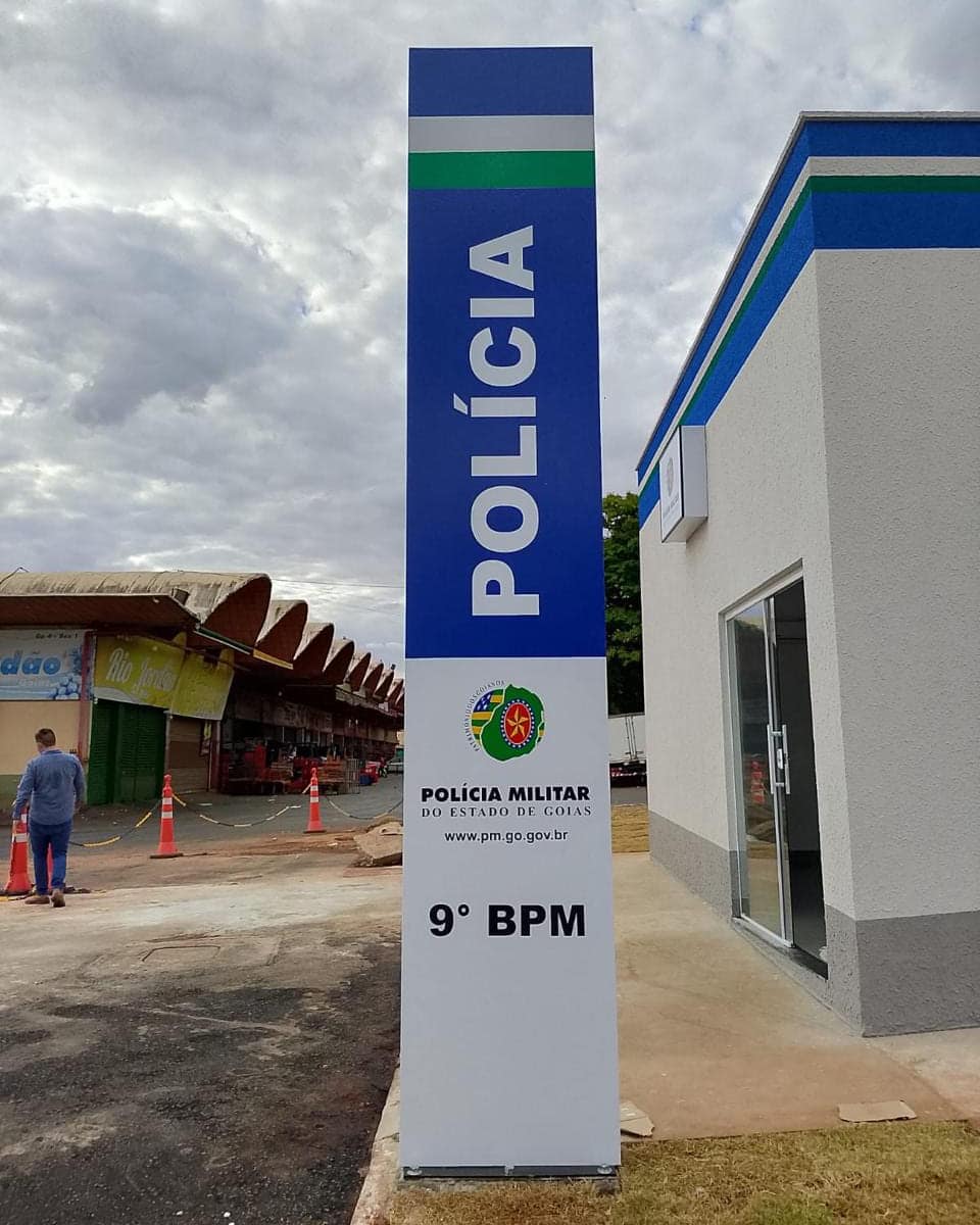 Totem vertical de identificação do 9º Batalhão da Polícia Militar de Goiás, em azul e branco, na entrada da unidade