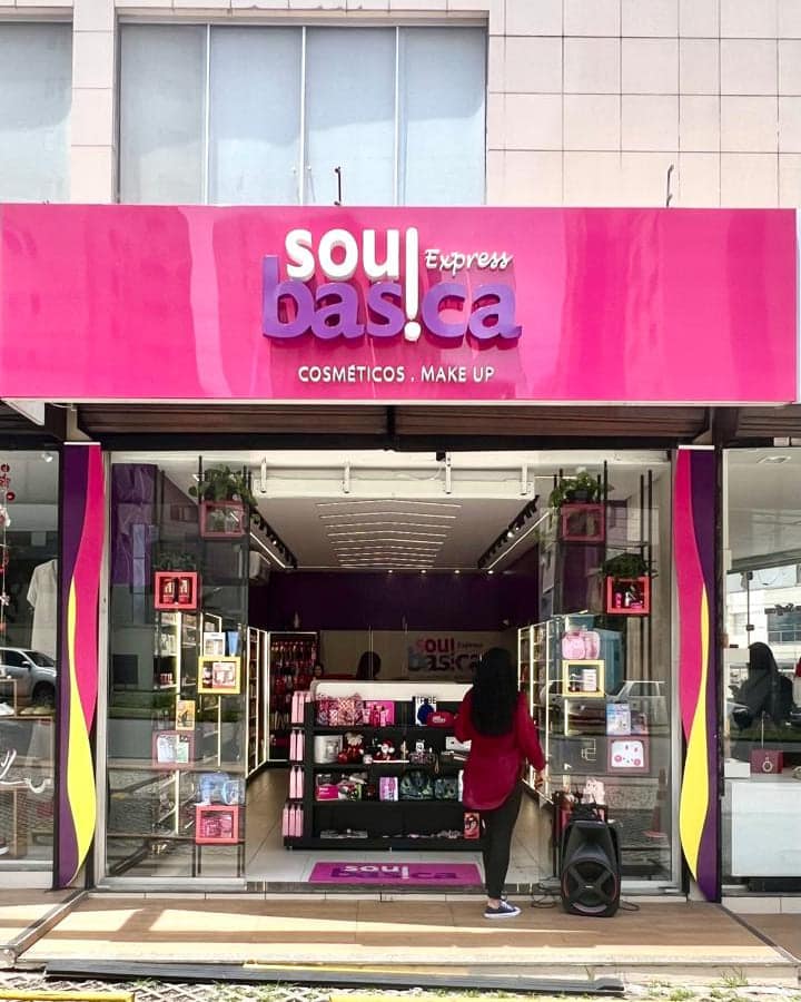 Fachada da Sou Básica Express em rosa, com a marca em letra caixa sobre a testeira e a loja aberta abaixo