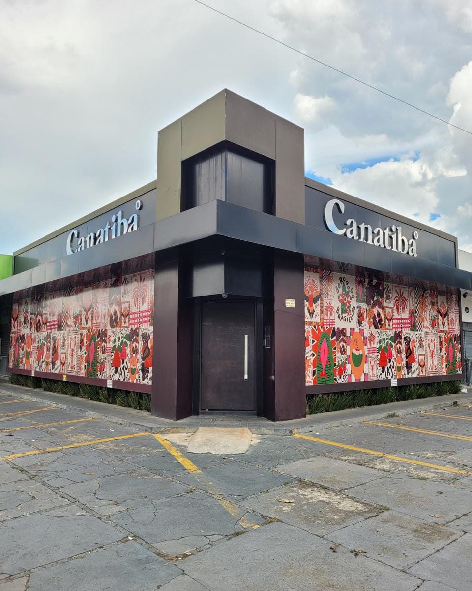Loja de esquina da Canatibá com fachada em ACM escuro, a marca em letra caixa e as vitrines cobertas com adesivo impresso floral