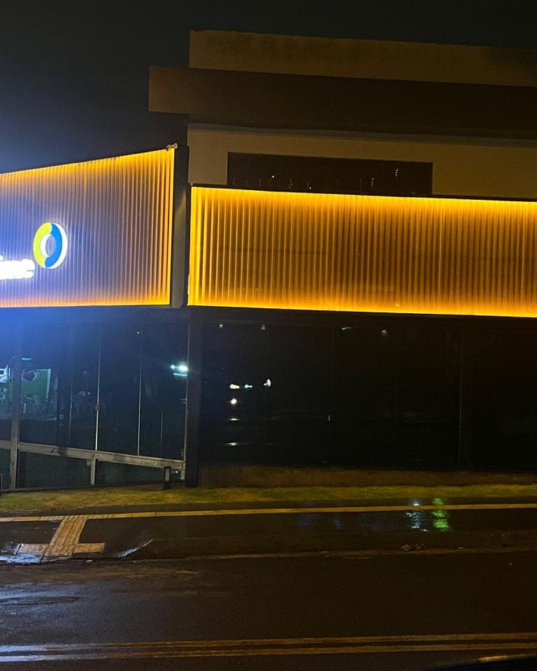 Fachada da Chopp Time à noite, com perfil de LED contornando o volume e o letreiro aceso no canto