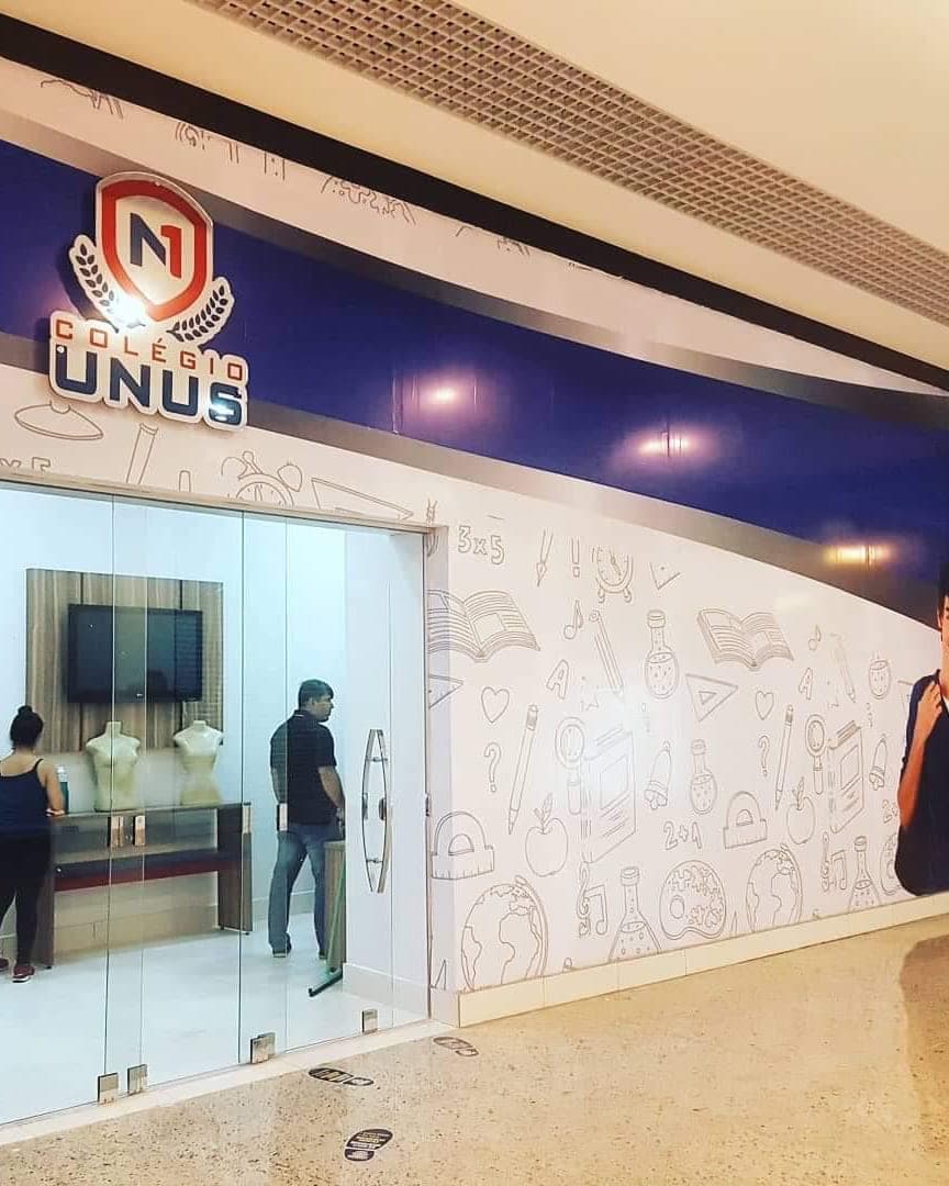 Loja do Colégio Unus em shopping, com a parede revestida de adesivo ilustrado e a marca em letra caixa sobre a entrada