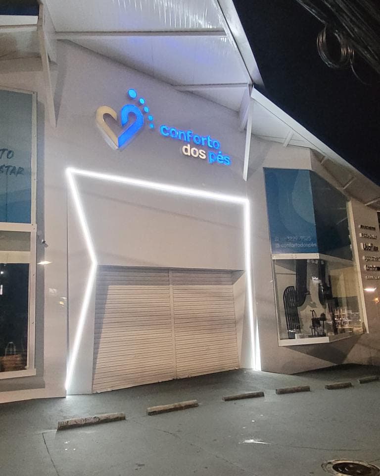 Fachada da Conforto dos Pés à noite, com a marca iluminada e perfil de LED contornando a entrada