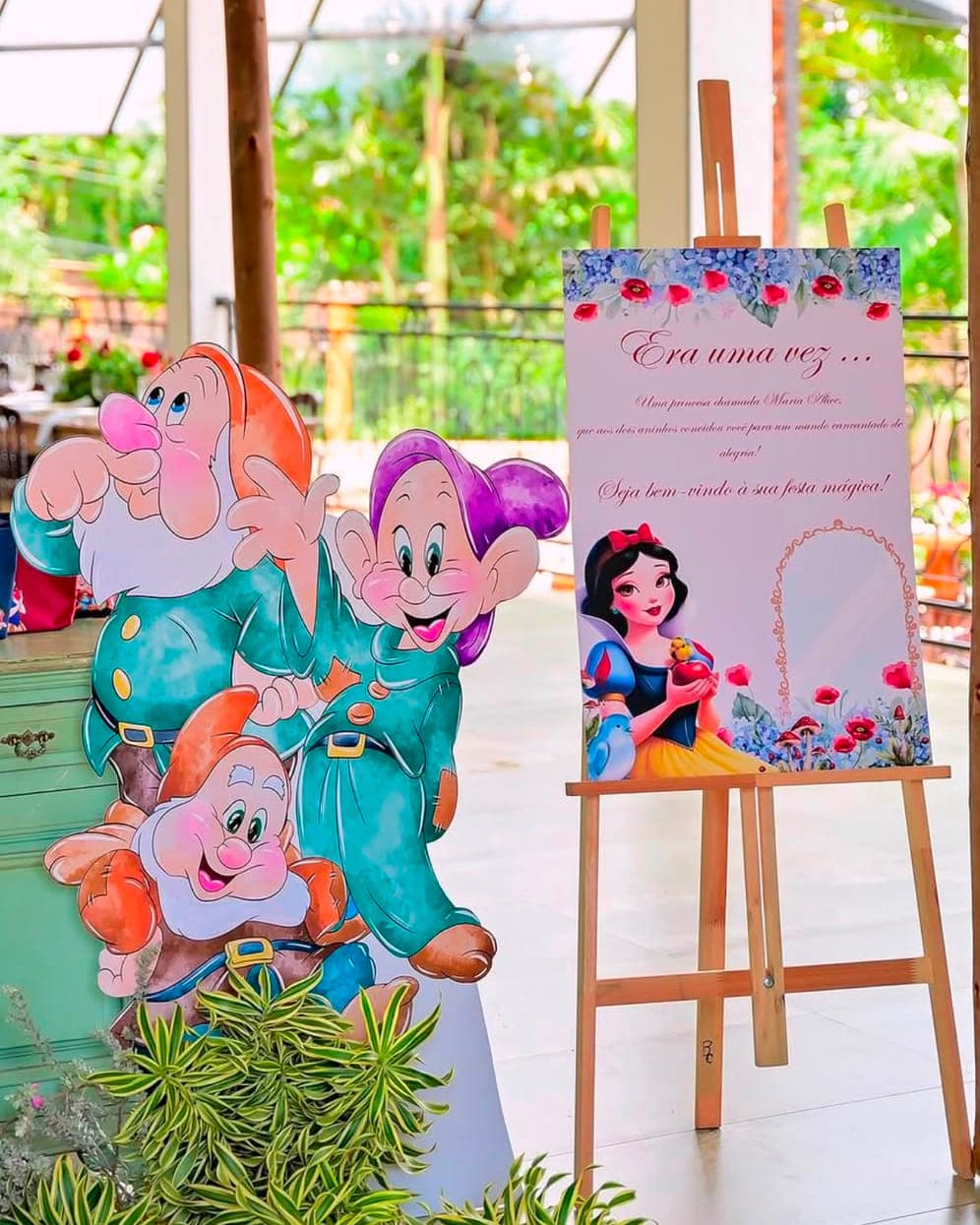 Display recortado dos anões da Branca de Neve ao lado da placa de boas-vindas da Maria Alice sobre cavalete, em festa de dois anos