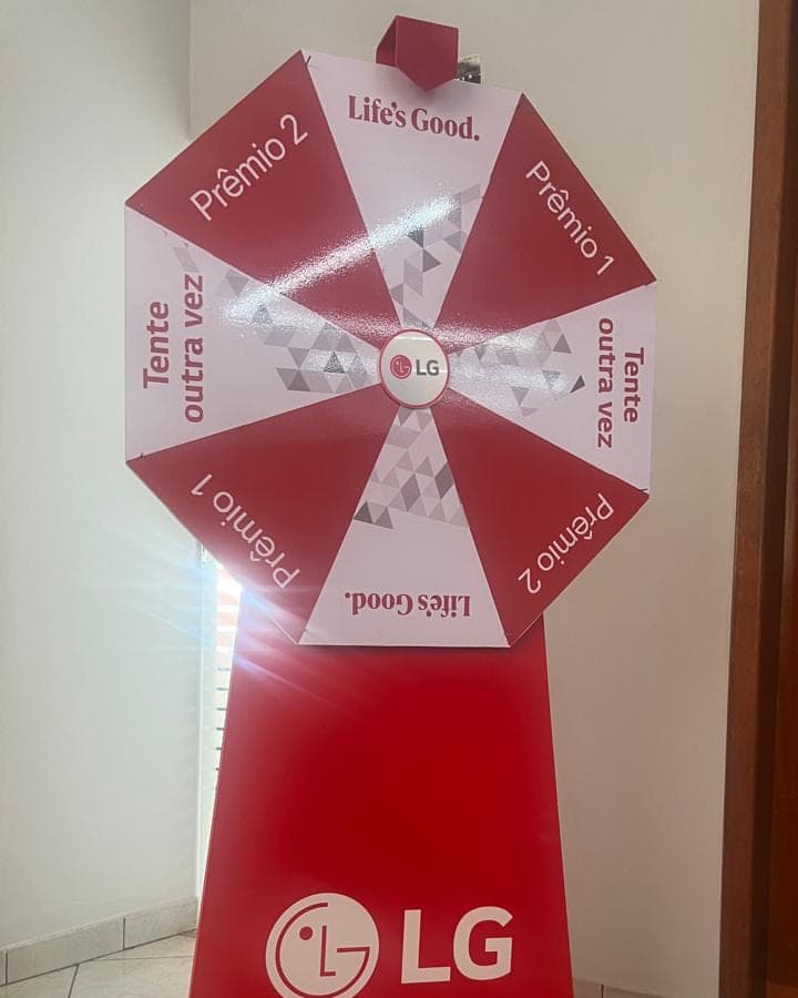 Roleta promocional da LG em vermelho e branco, com setores de prêmio, montada sobre base cônica