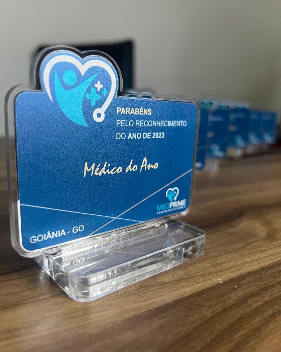 Placa de homenagem Médico do Ano da Medprime, em acrílico azul impresso com base cristal, com outras iguais ao fundo