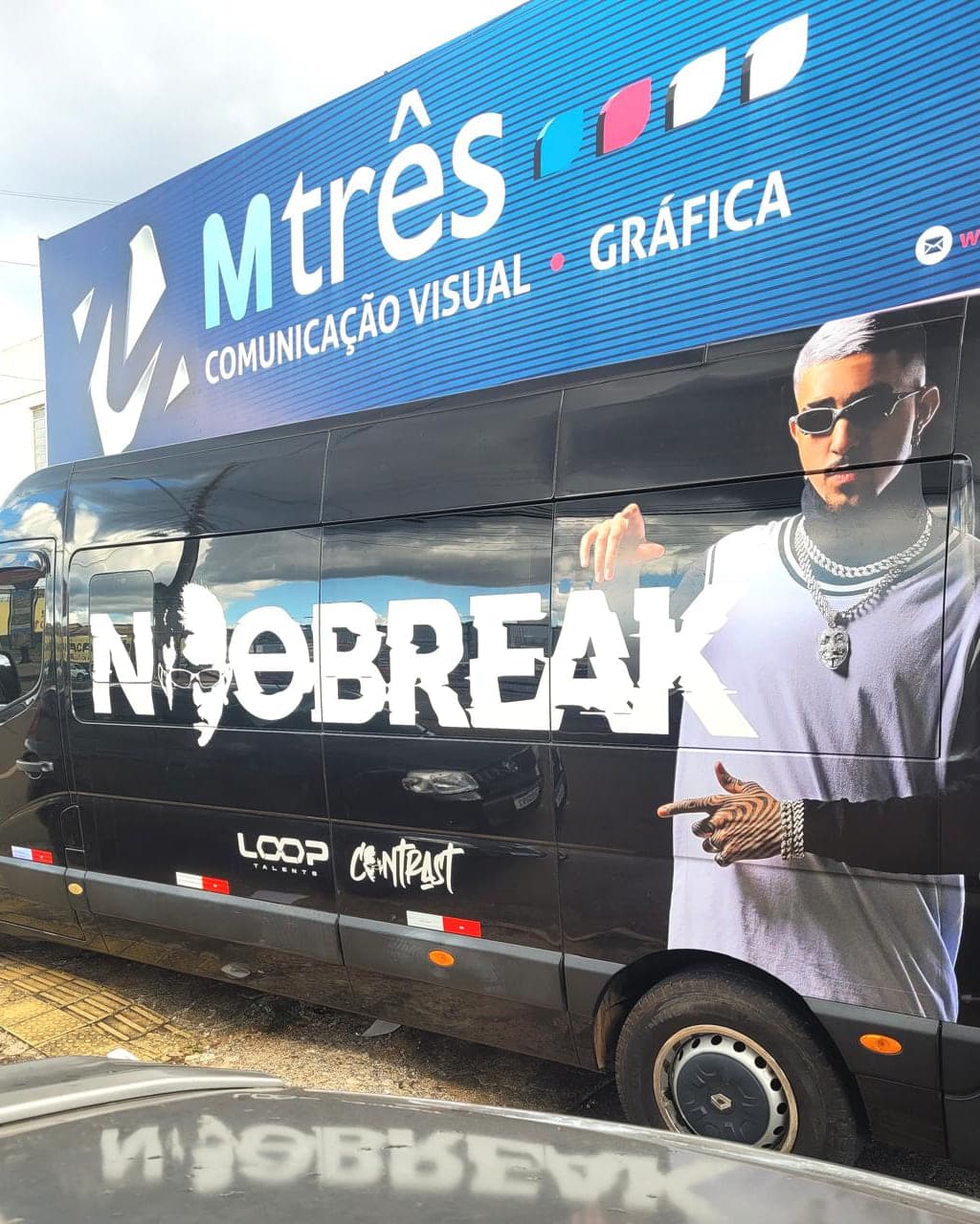Van do artista Noobreak envelopada em preto, com o nome em branco e a foto dele impressa na lateral
