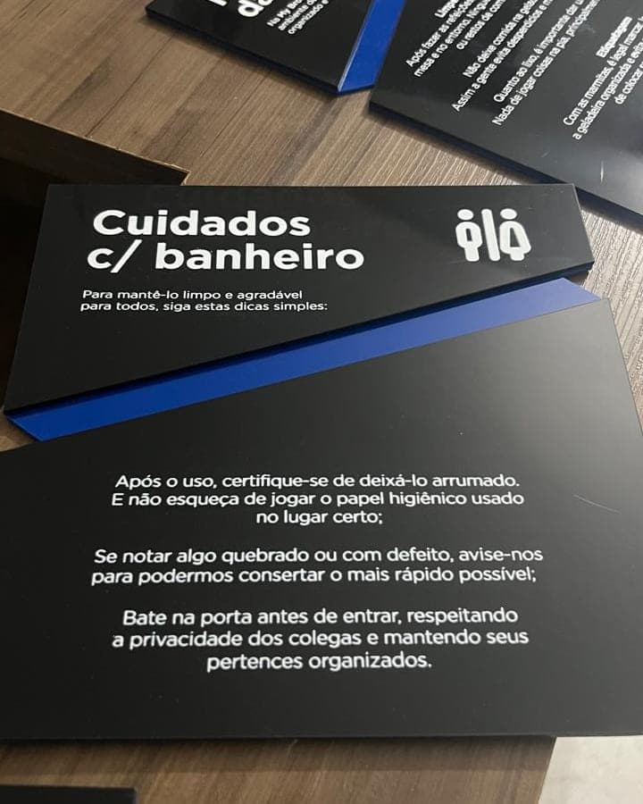 Placas internas da Ölö em acrílico preto com faixa azul, impressas com as regras da copa e do banheiro