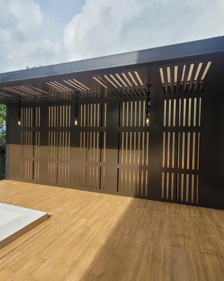 Painel vazado em chapa preta cortada a laser, fechando uma varanda com deck de madeira