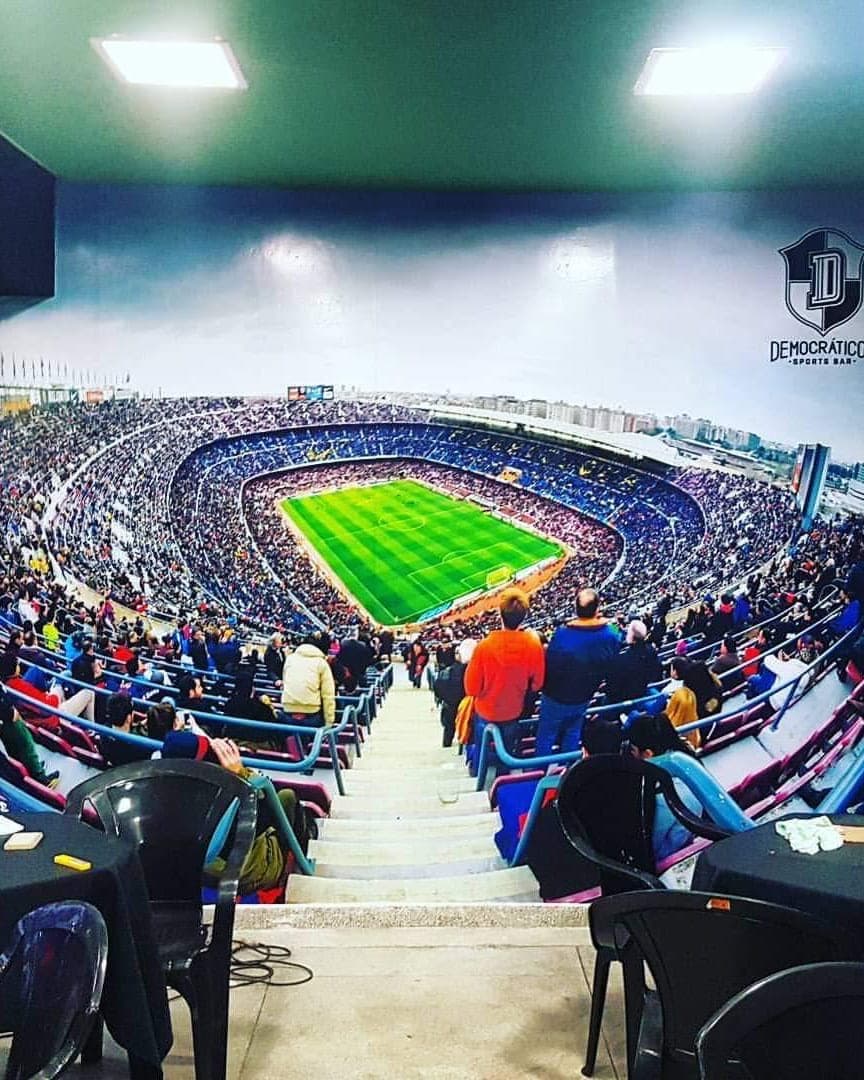Parede do Democráticos Sports Bar revestida com adesivo impresso de um estádio lotado, do teto ao piso