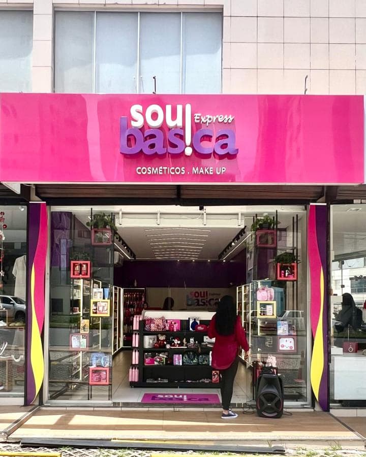 Fachada da Sou Básica Express em rosa, com a marca em letra caixa sobre a testeira e a loja aberta abaixo