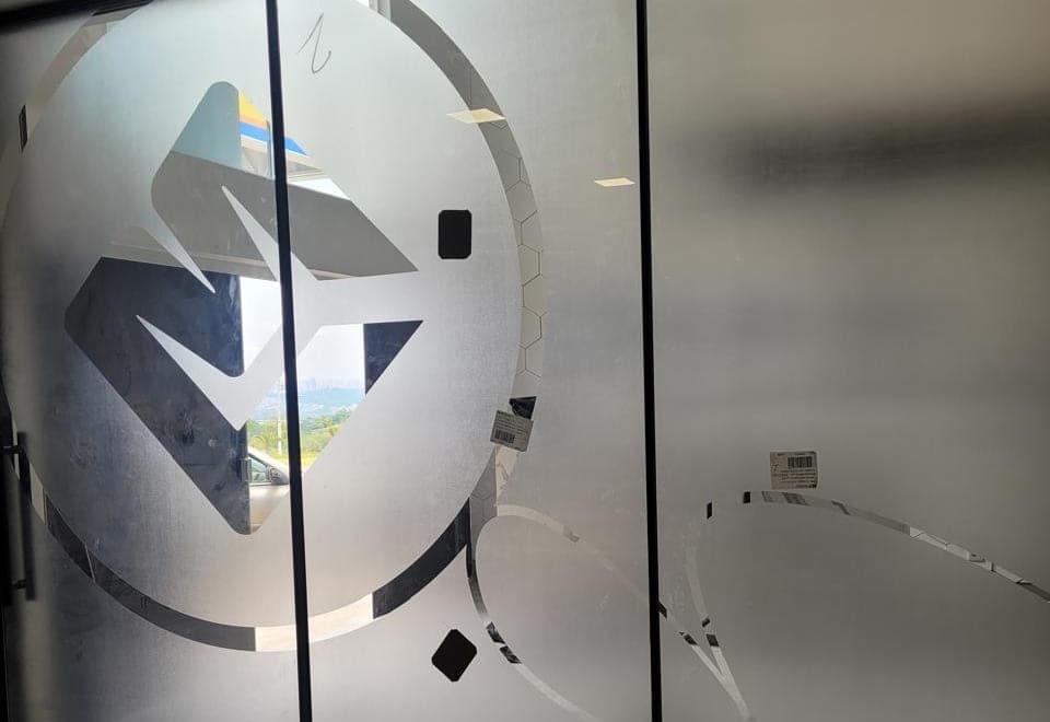 Divisória de vidro com aplicação de vinil jateado e a marca recortada no meio