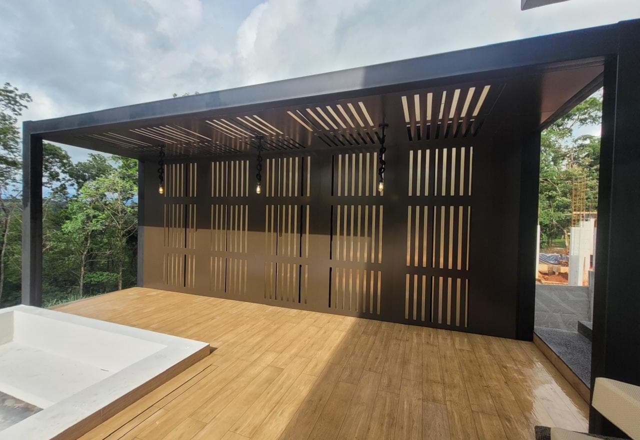 Painel vazado em chapa preta cortada a laser, fechando uma varanda com deck de madeira