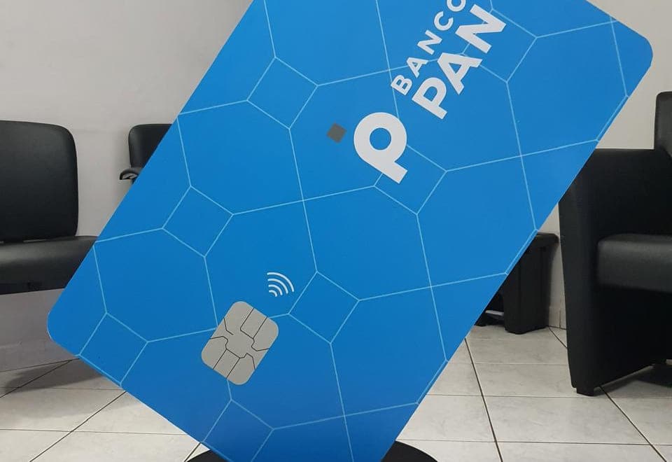 Display de piso em formato de cartão gigante, montado sobre base circular com rodízios