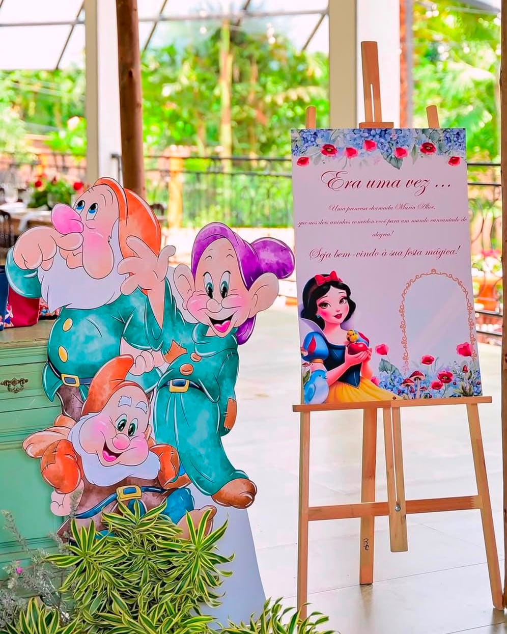 Display recortado de personagens ao lado de placa de boas-vindas sobre cavalete, em festa de tema infantil