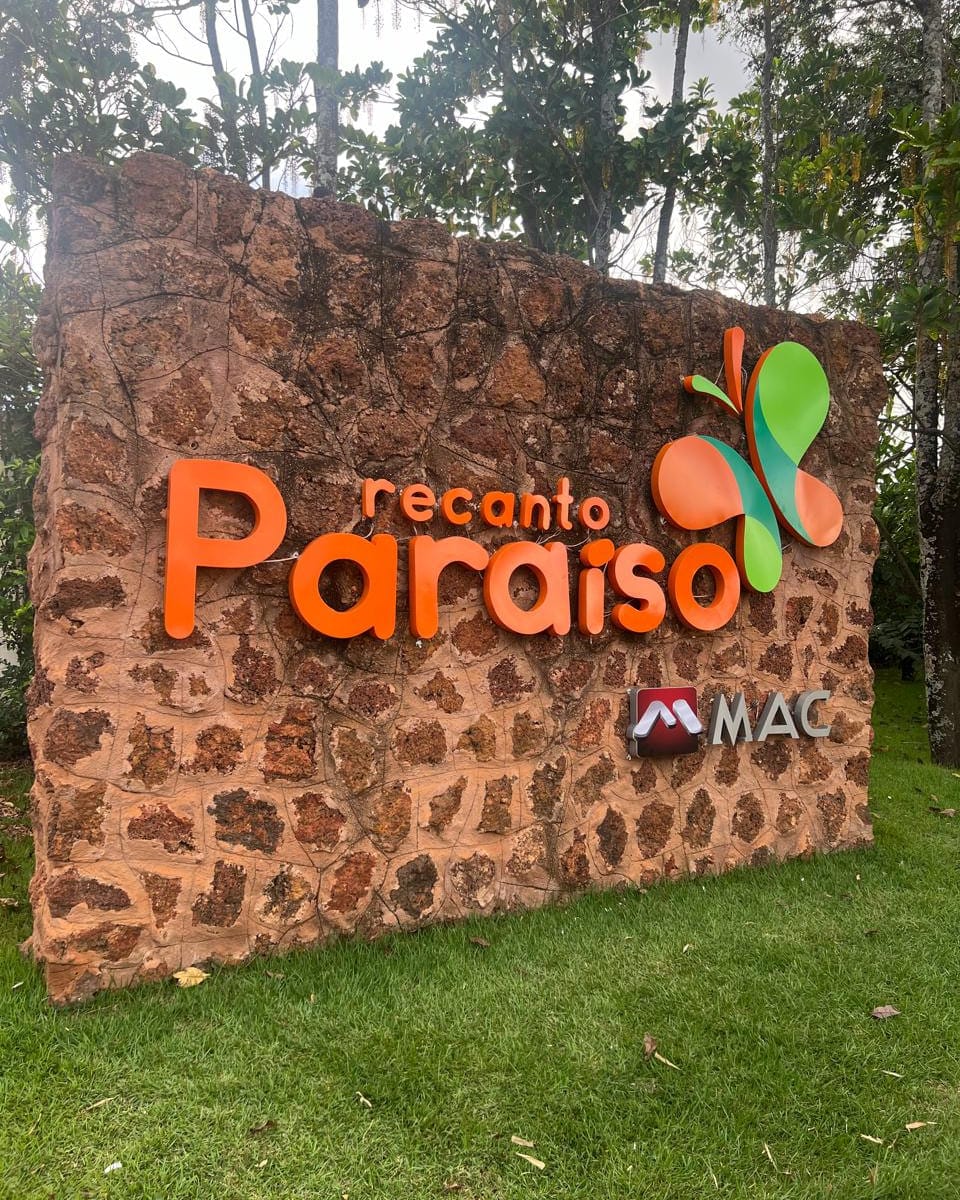 Letra caixa em acrílico laranja da marca Recanto Paraíso aplicada sobre muro de pedra