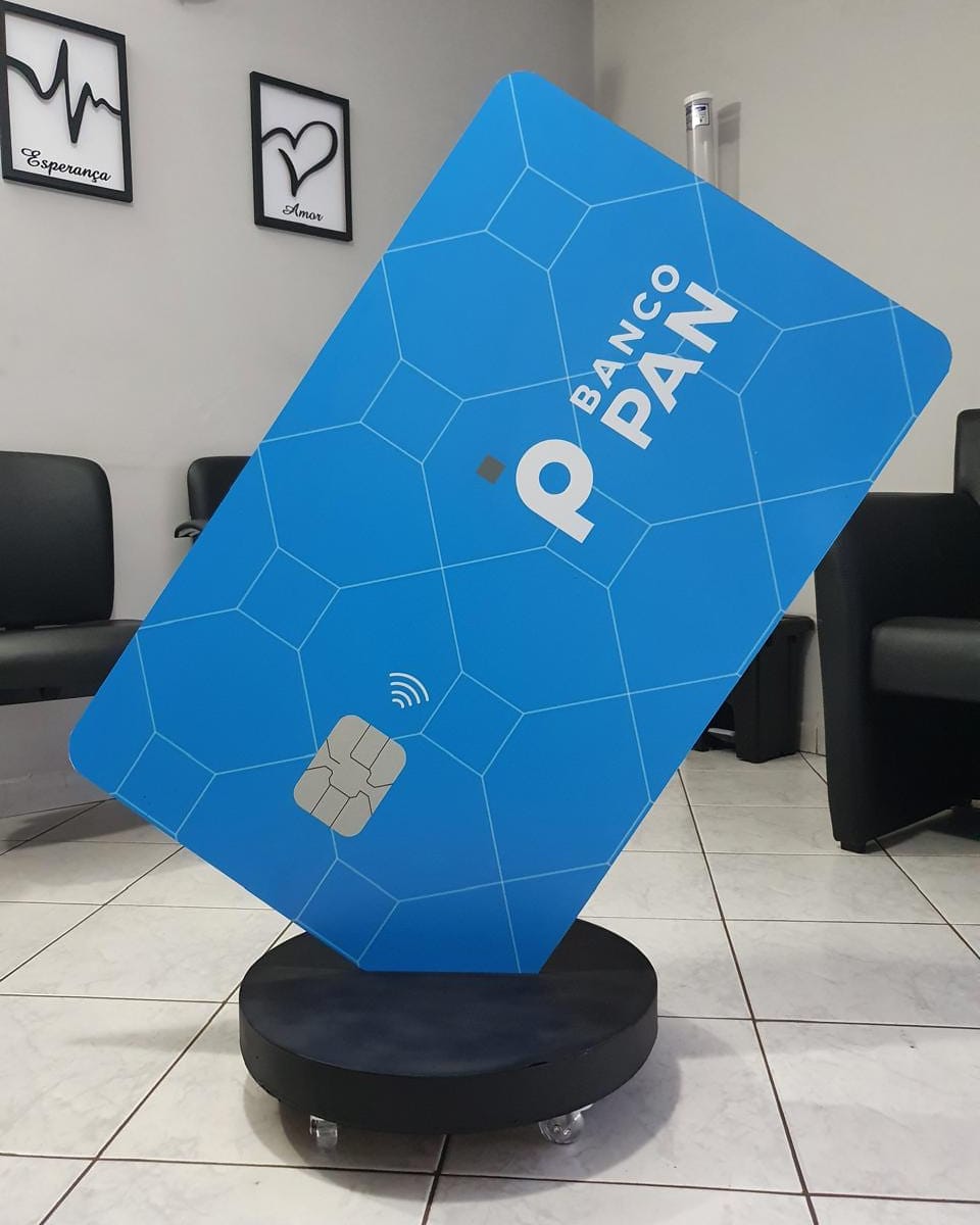 Display de piso do Banco PAN em formato de cartão gigante azul, montado sobre base circular